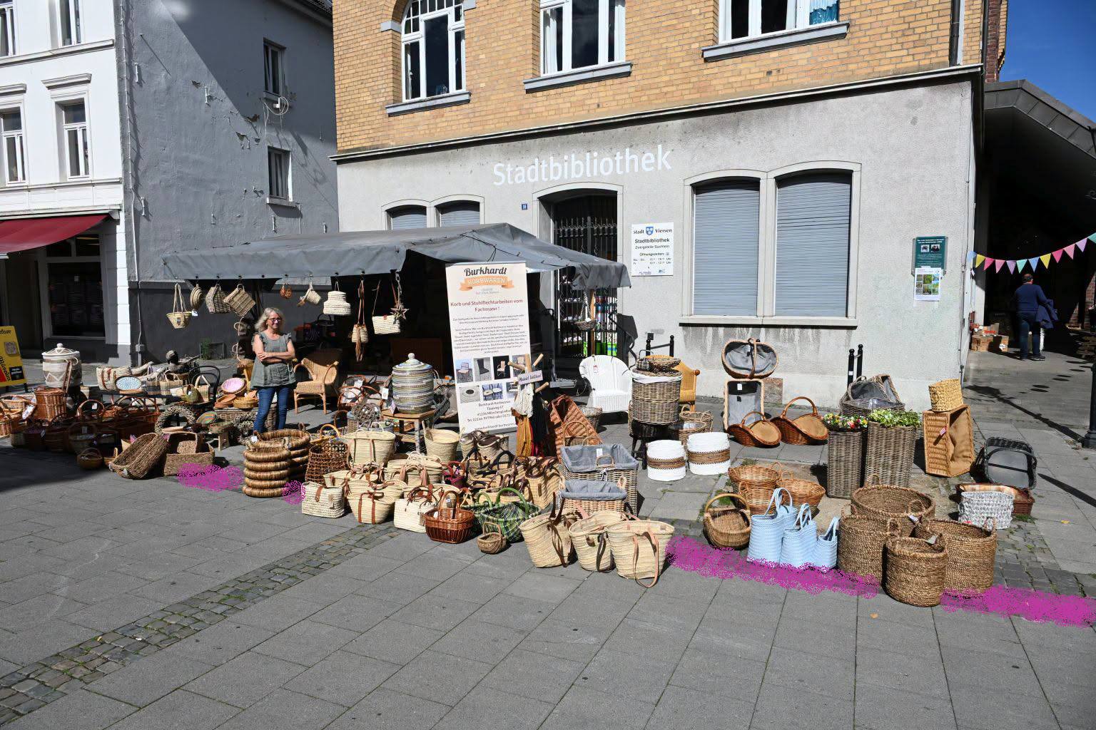 Korbwaren-Stand beim Irmgardisfest vor der Stadtbibliothek, die magenta markierten taktilen Streifen durchziehen den Standbereich.